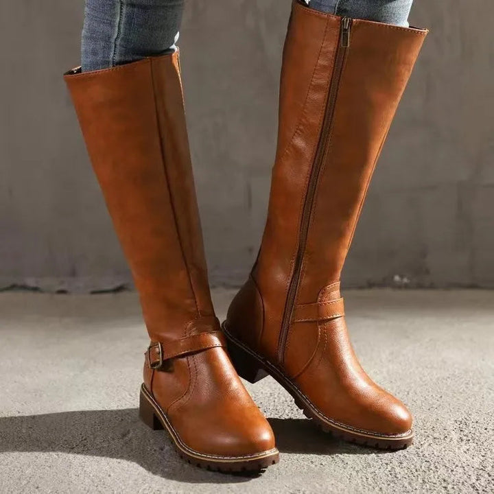 Bottes hautes camel portées avec un jean, vues de côté avec la fermeture éclair et la boucle sur la cheville. 1