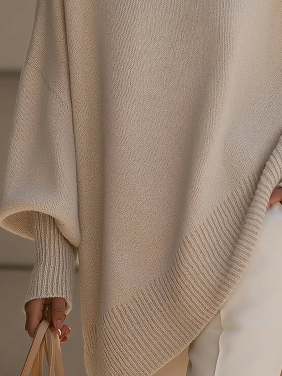 Détail de l'ourlet asymétrique côtelé et du poignet côtelé du pull beige, la main tenant un sac. 3