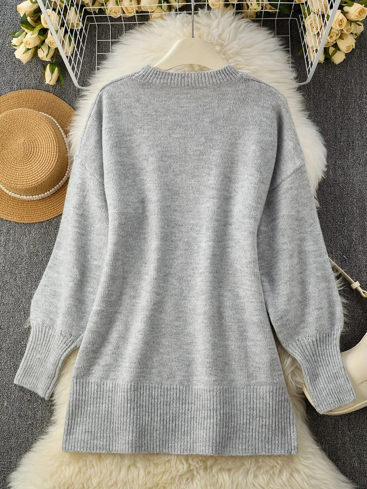 Pull gris vu de dos posé à plat sur une fourrure blanche, avec chapeau de paille et fleurs décoratives. 10