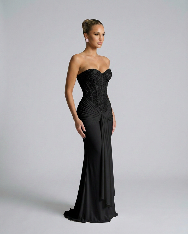 Robe noire portée en trois-quarts, montrant le bustier brodé de sequins et le drapé qui retombe sur la jupe 2