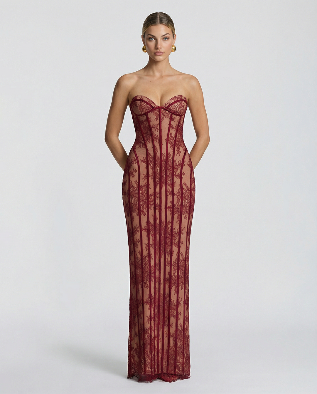 Mannequin de face portant la robe longue bustier en dentelle bordeaux, coupe ajustée sur fond gris clair. 1