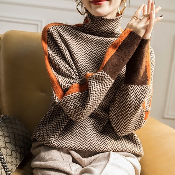 Femme assise sur un canapé, mains jointes, portant le pull à chevrons marron et beige aux manches rayées d'orange. 4