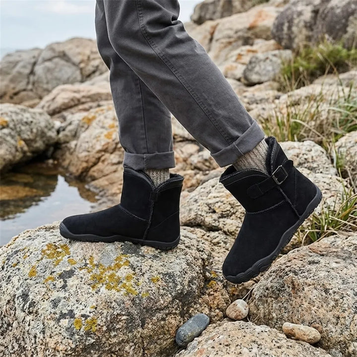 Bottes noires portées sur des rochers couverts de lichen, avec pantalon gris et chaussettes en laine 11