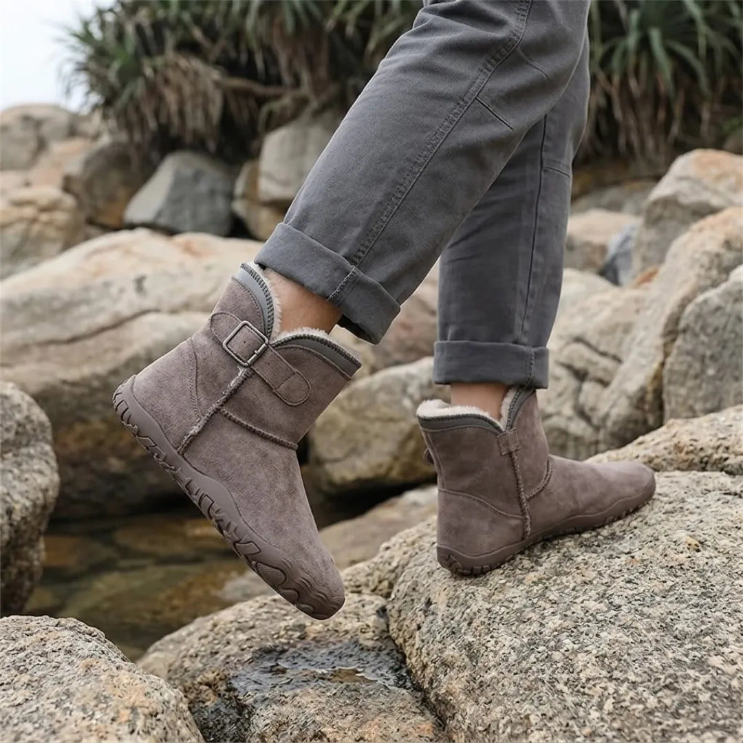 Pieds portant les bottes taupe, pantalon gris retroussé, en marchant sur des rochers au bord de l'eau 38