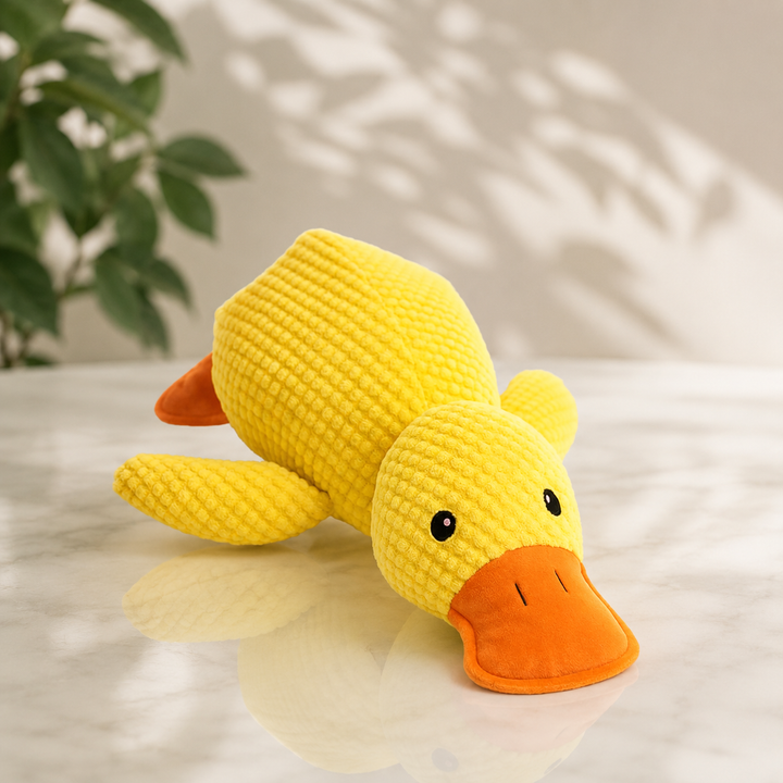 Canard en peluche jaune gaufrée au bec orange, posé sur une table en marbre, vue de trois quarts 1