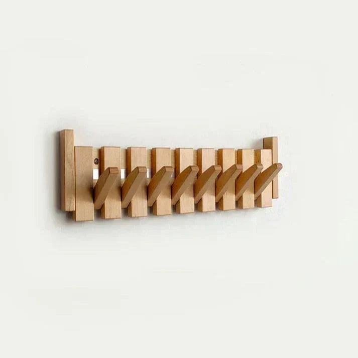 Porte-manteau en bois clair avec tous les crochets abaissés en diagonale, vu de face sur un mur blanc. 9