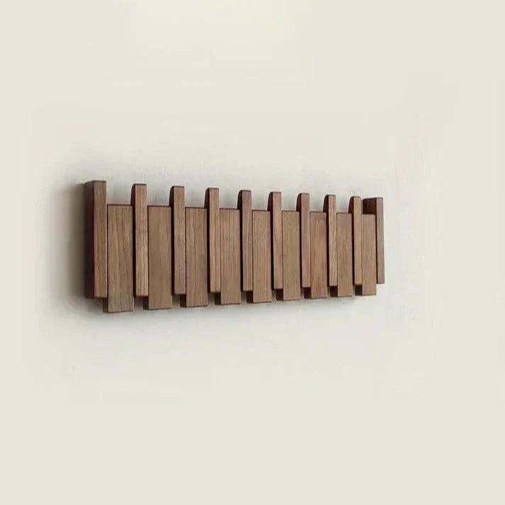 Porte-manteau en bois foncé avec crochets repliés, formant une barre murale aux lames de hauteurs irrégulières. 10