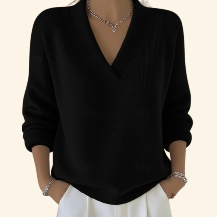 Pull noir à col en V et manches longues, porté par une femme avec pantalon blanc et bracelets. 4