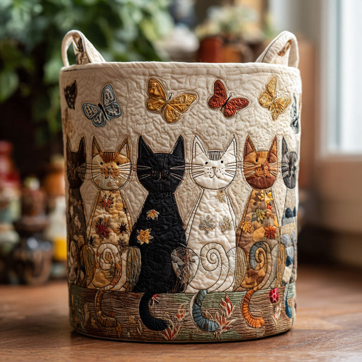 Panier rond matelassé crème avec rangée de chats appliqués et papillons colorés, posé seul sur un plancher en bois près d'une fenêtre. 1