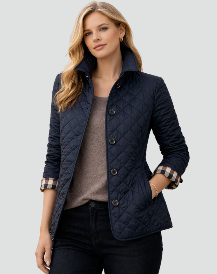 Veste matelassée bleu marine portée sur un haut taupe et un pantalon sombre, une main dans la poche, poignets à carreaux visibles. 5