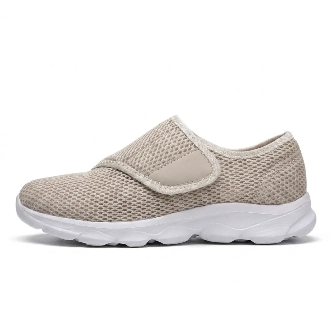 Profil d'une chaussure beige en mesh alvéolé avec sangle auto-agrippante sur le cou-de-pied et semelle blanche à amorti. 28