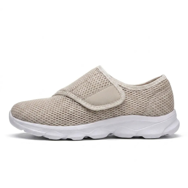 Profil d'une chaussure beige en mesh alvéolé avec sangle auto-agrippante sur le cou-de-pied et semelle blanche à amorti. 28