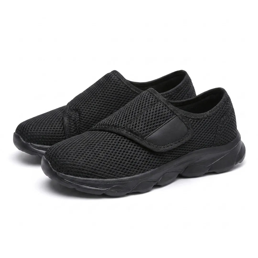 Paire de chaussures toutes noires en mesh aéré à sangle auto-agrippante, vue trois-quarts sur fond blanc. 16
