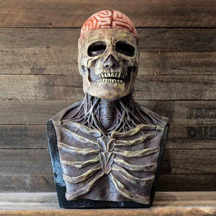 Masque de squelette en latex vu de face sur un présentoir en bois, avec cerveau rose apparent, cage thoracique et cou sculptés. 1