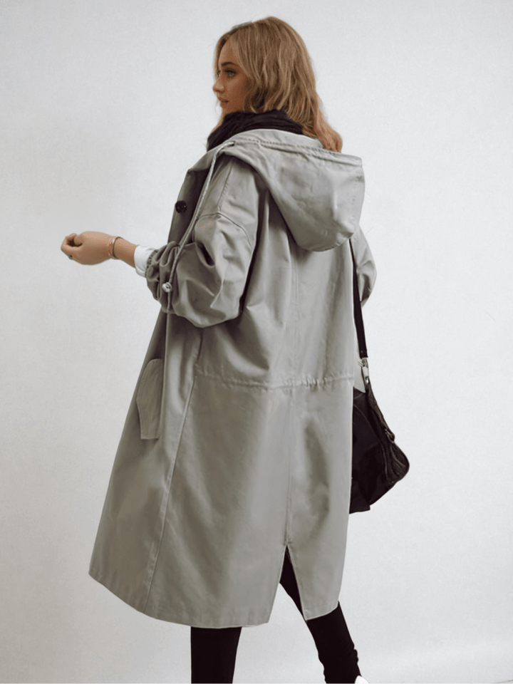 Trench gris à capuche vu de dos et de côté, cordon à la taille, poche plaquée, fente arrière et sac noir à l'épaule. 8