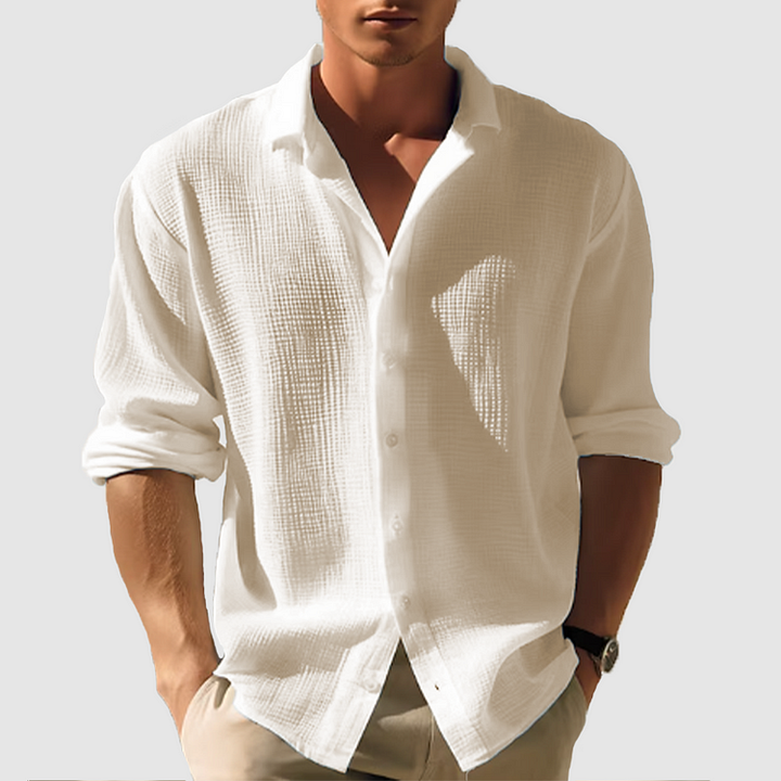Homme portant la chemise texturée blanc cassé, manches retroussées, col ouvert, avec un pantalon beige et une montre. 5