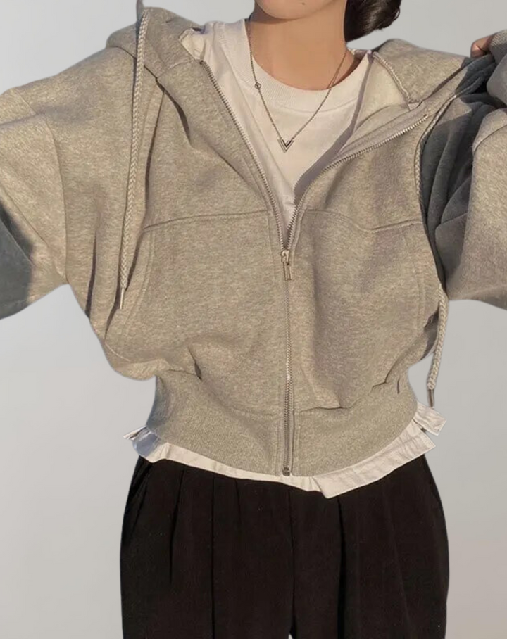 Sweat gris chiné zippé porté par-dessus un t-shirt blanc, avec un pantalon noir, bras écartés pour montrer la coupe. 5