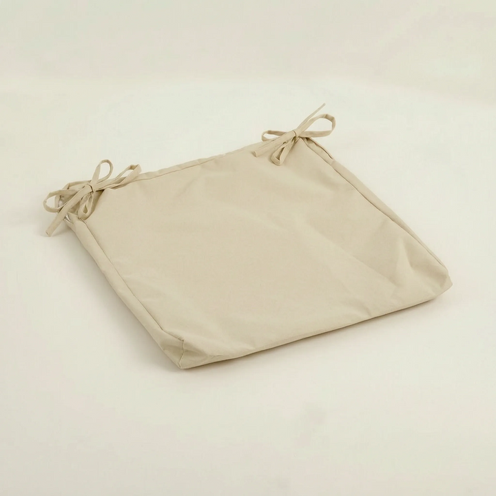 Coussin crème clair posé à plat, avec deux liens noués à l'arrière du dessus 13