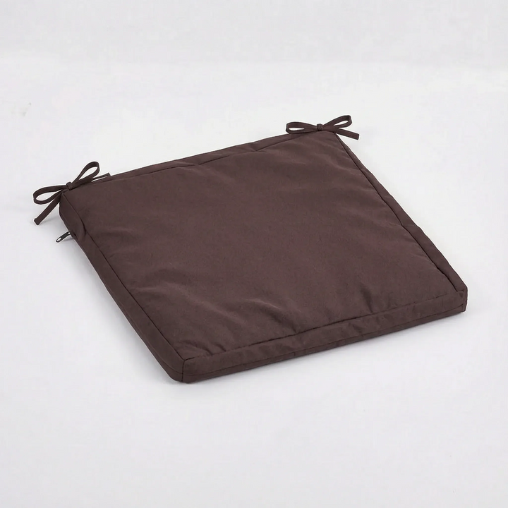 Coussin marron chocolat posé à plat, avec deux liens noués et la fermeture à glissière sur la gauche 15