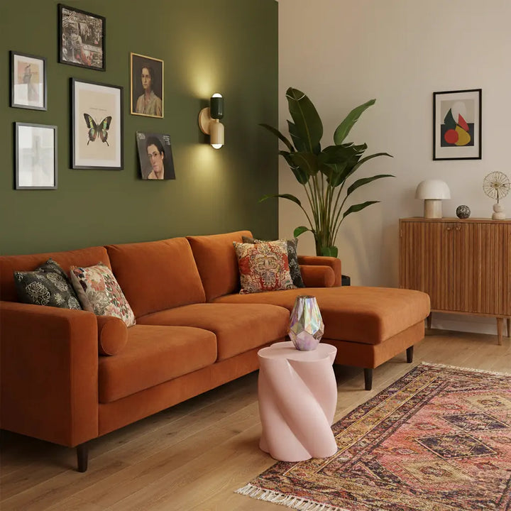 Applique verte et crème allumée sur un mur vert olive, au-dessus d'un canapé d'angle en velours orange. 9