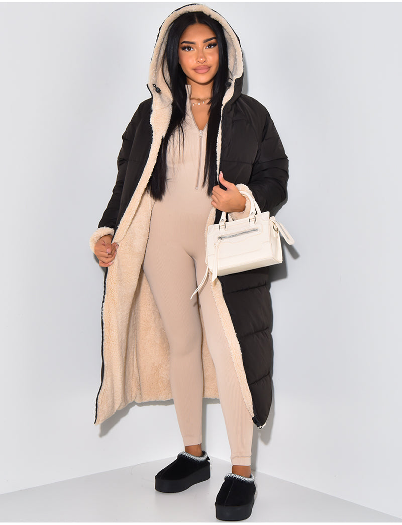 Femme portant le manteau matelassé noir ouvert, qui laisse voir la doublure en fourrure synthétique beige, avec une combinaison côtelée beige. 1
