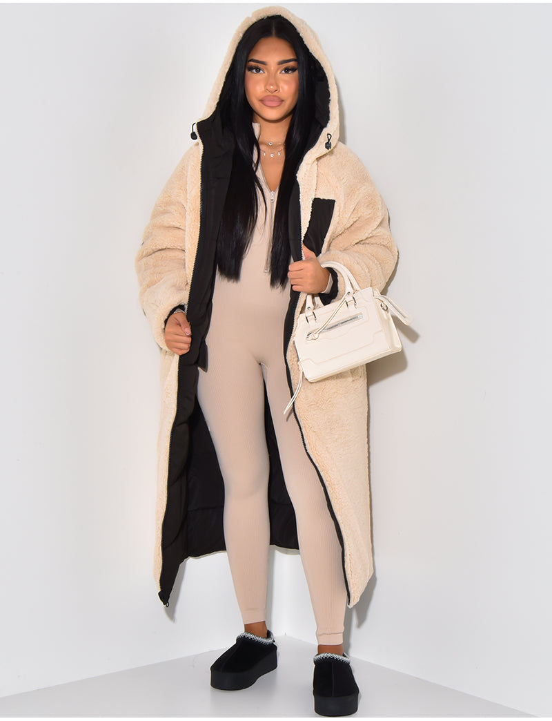 Femme portant le manteau côté fourrure beige ouvert, qui laisse voir l'intérieur matelassé noir, capuche relevée, avec un sac blanc à la main. 8