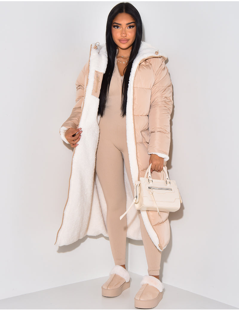 Femme portant le manteau matelassé beige rosé ouvert, qui laisse voir la doublure en fourrure blanche, avec un petit sac crème à la main. 5