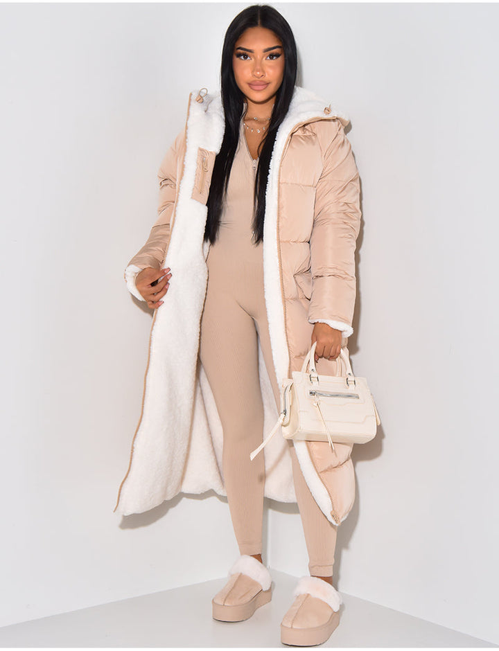 Femme portant le manteau matelassé beige rosé ouvert, qui laisse voir la doublure en fourrure blanche, avec un petit sac crème à la main. 5