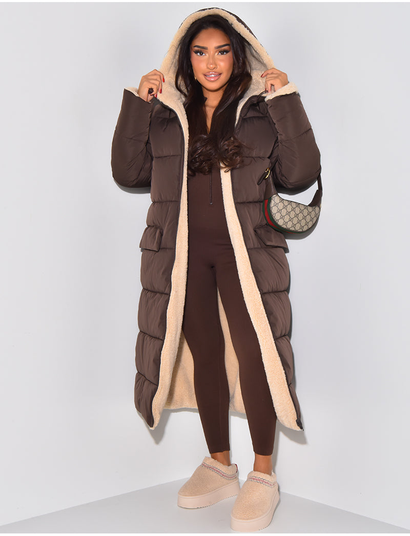 Femme portant le manteau matelassé marron ouvert, capuche relevée et doublure en fourrure beige visible, avec une combinaison marron. 2