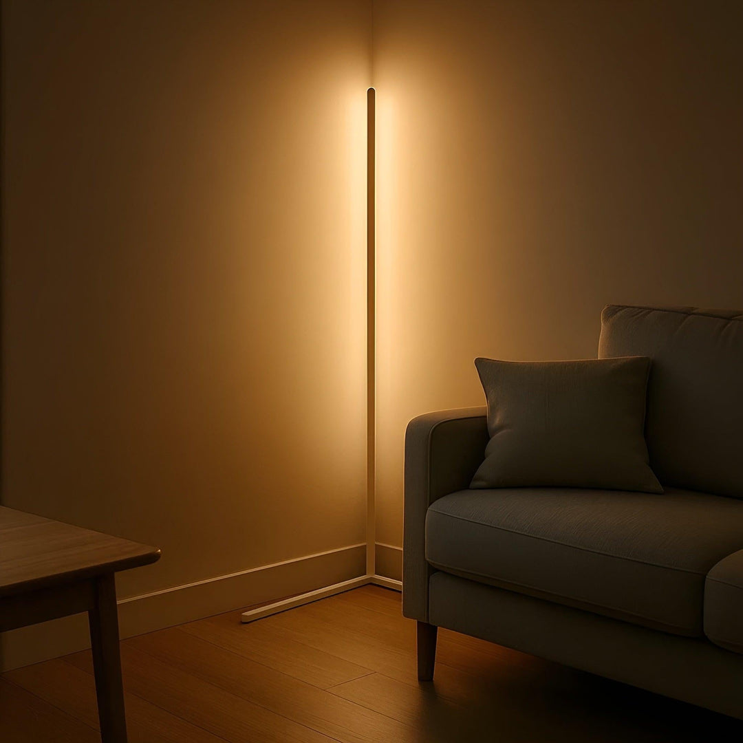 Lampe d'angle blanche allumée dans l'ambiance tamisée d'un salon, à côté d'un canapé gris et d'une table en bois. 6