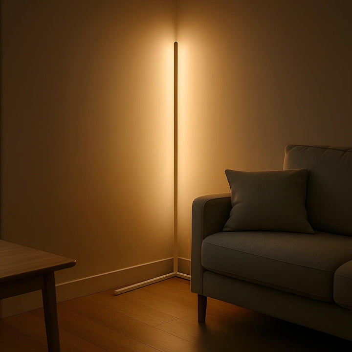 Lampe d'angle blanche allumée dans l'ambiance tamisée d'un salon, à côté d'un canapé gris et d'une table en bois. 6