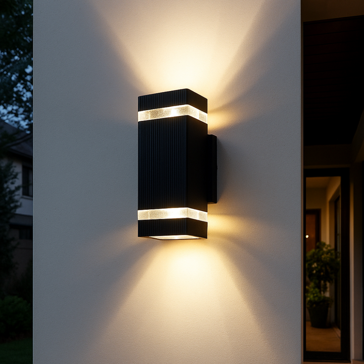 Applique rectangulaire noire striée à deux bandes lumineuses, allumée le soir sur un mur blanc 1