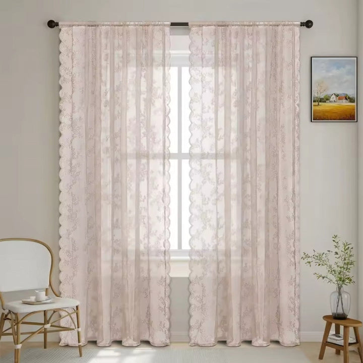 Deux panneaux de dentelle florale rose pâle à bord festonné devant une fenêtre, avec chaise blanche, plante et tableau. 9