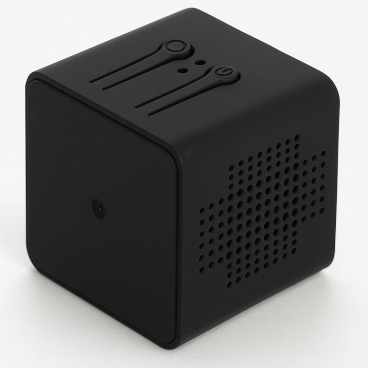 Boîtier cube noir mat vu de trois quarts, montrant les deux boutons en relief sur le dessus et la grille perforée sur le côté. 6