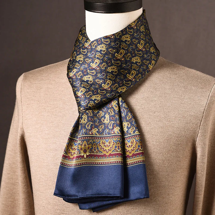 Foulard en soie bleu marine à motif cachemire doré, bordure bleue ornée de rouge et d'or, sur mannequin avec pull beige. 12