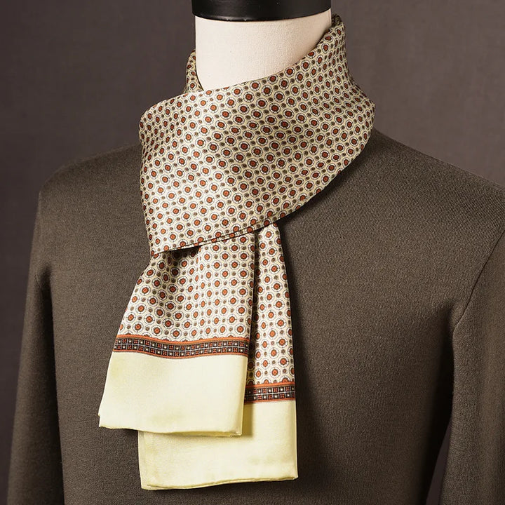 Foulard en soie crème à petits motifs orange et bordure jaune pâle, porté sur un mannequin avec pull kaki. 9