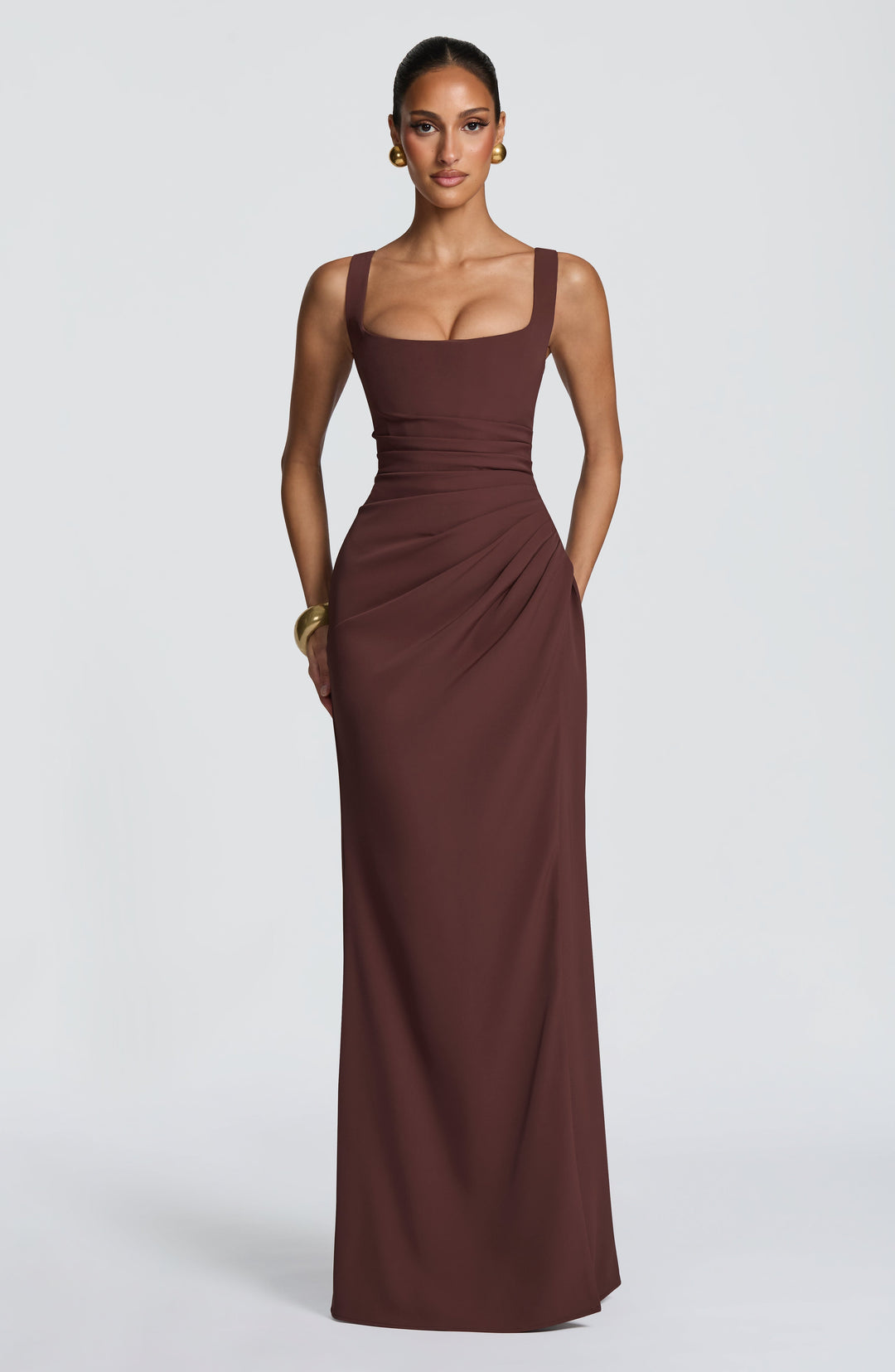 Robe marron chocolat portée de face, mains dans le dos, sans fente visible, drapé sur la hanche et bracelet doré. 4