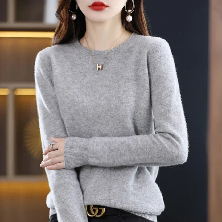 Pull col rond gris clair porté avec un pantalon noir et une ceinture, bras repliés devant 20