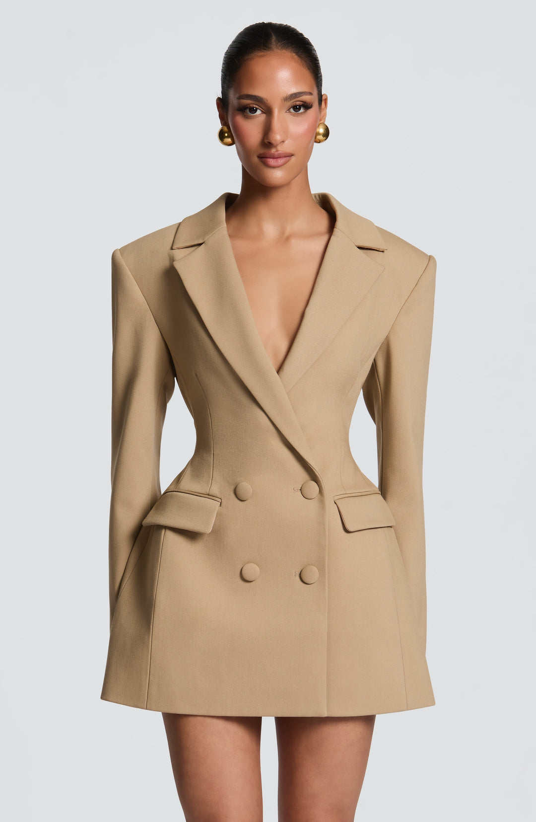 Robe blazer beige camel vue de face, double boutonnage, taille très cintrée, épaules structurées et grosses boucles d'oreilles dorées. 18