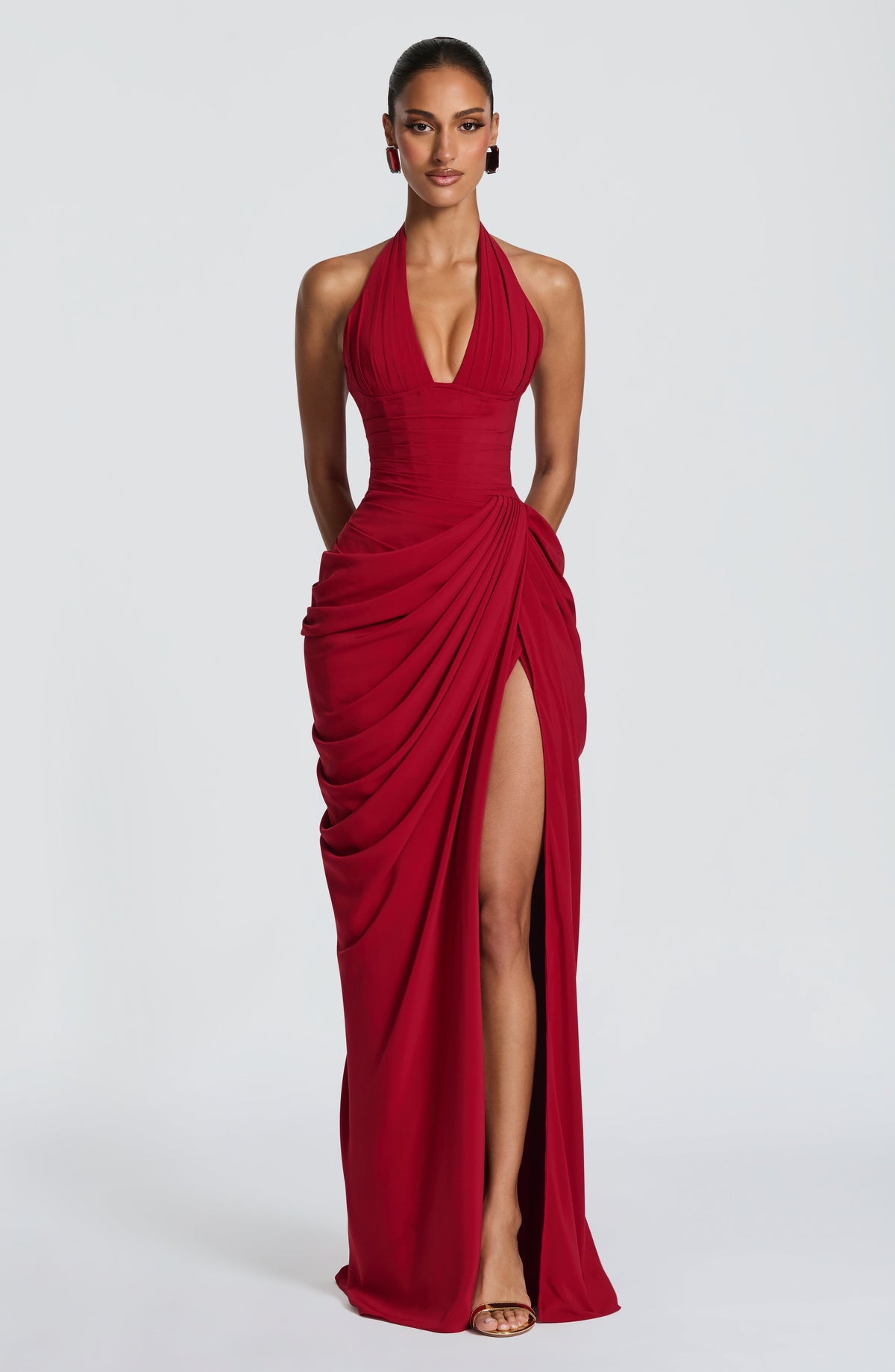 Robe rouge portée de face, décolleté plongeant, bustier plissé façon corset et jupe drapée à fente haute. 16