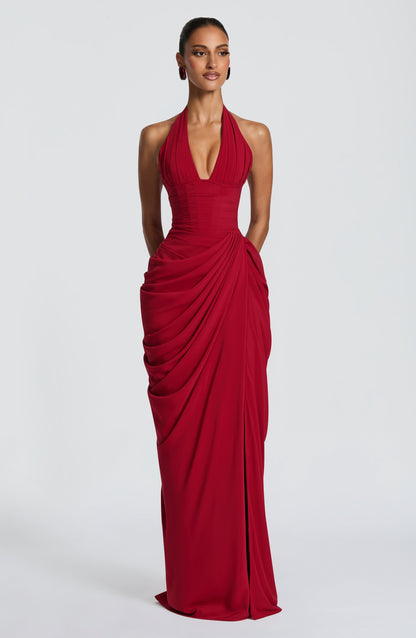 Mannequin de face en robe longue rouge à bustier corseté, décolleté plongeant et jupe drapée, fond de studio gris clair. 21