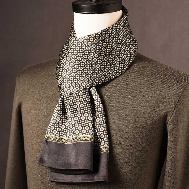 Foulard en soie noir à petits médaillons dorés et blancs, bordure grise, drapé sur un mannequin avec pull kaki. 7