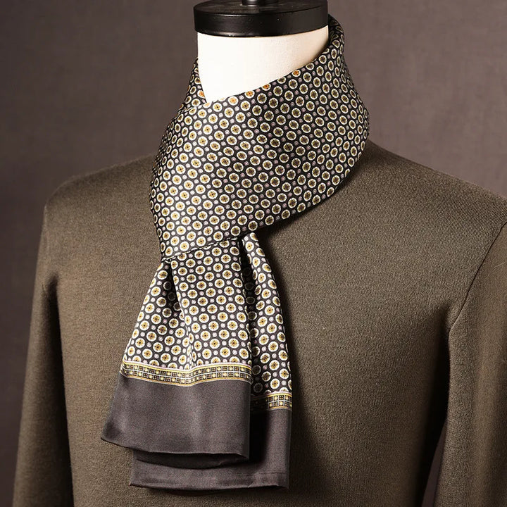 Foulard en soie noir à petits médaillons dorés et blancs, bordure grise, drapé sur un mannequin avec pull kaki. 7
