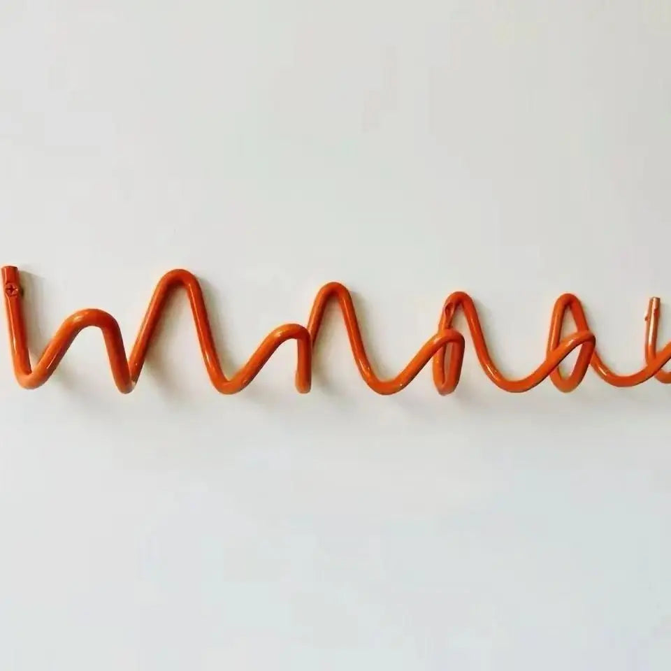 Portant orange ondulé fixé à un mur blanc, vu de face, avec ses boucles métalliques et une vis à l'extrémité gauche. 12