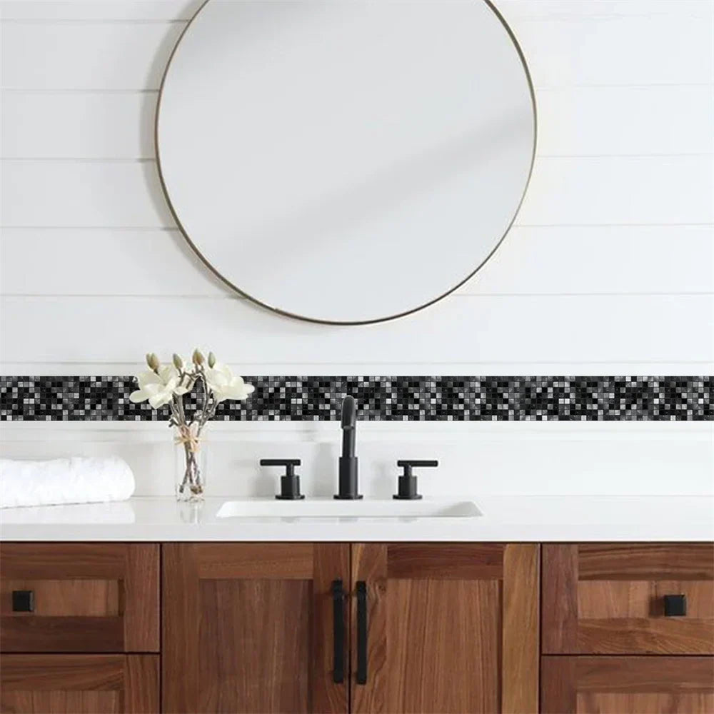 Frise de mosaïque noire et grise collée sur un mur blanc entre miroir rond et meuble de salle de bains 34