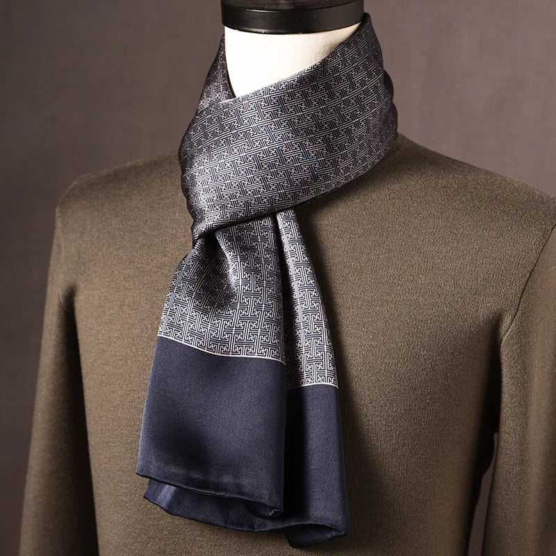 Foulard en soie gris et bleu marine à motif de grecques géométriques, large bordure marine, sur mannequin avec pull kaki. 10