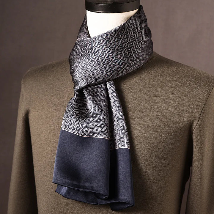 Foulard en soie gris et bleu marine à motif de grecques géométriques, large bordure marine, sur mannequin avec pull kaki. 10