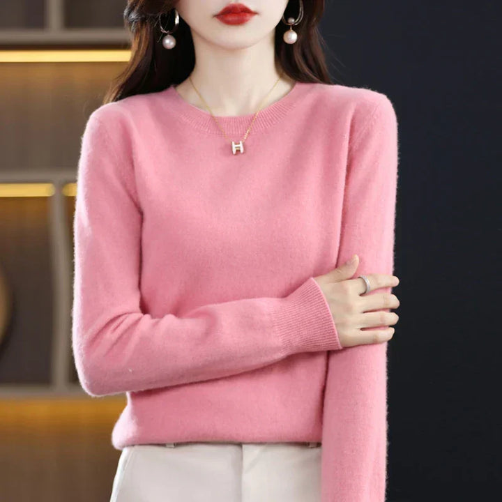 Pull col rond rose clair porté avec un pantalon crème, bras replié devant le buste 10