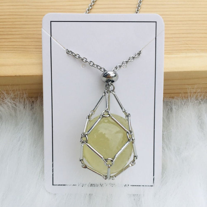 Collier argenté avec filet retenant une pierre jaune-vert pâle, présenté sur une carte blanche posée contre du bois clair. 9