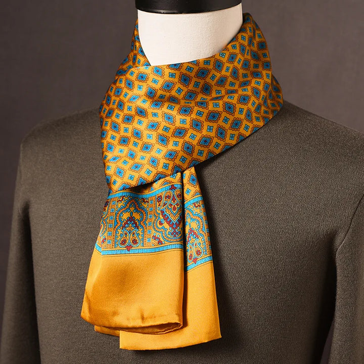 Foulard en soie jaune moutarde à losanges bleus et bordure ornementale, noué sur un mannequin avec pull kaki. 5